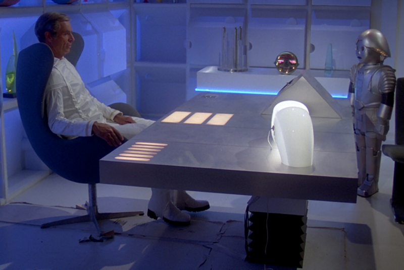 File:BR25 - Planet of the Slave Girls - Wood Wedges and Mess of Wire Under Huer's Chair and Desk.png